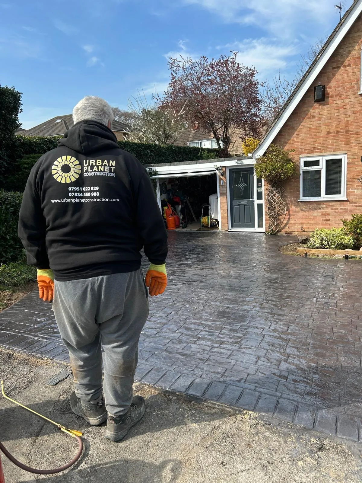 Urban Planet Construction team member sealing a newly laid imprinted concrete driveway