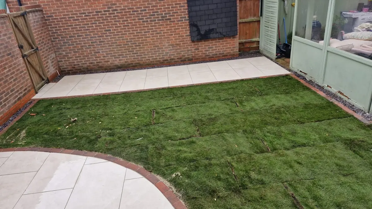 Garden renovation with new turf, brick-edged borders and a porcelain patio running along the back of the house