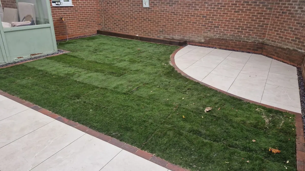 Curved porcelain patio corner beside a newly turfed lawn with brick edging