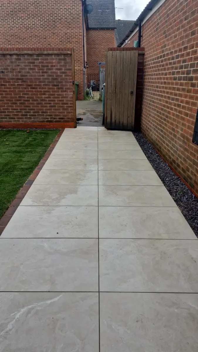 Porcelain path down the side of the house beside a strip of new turf
